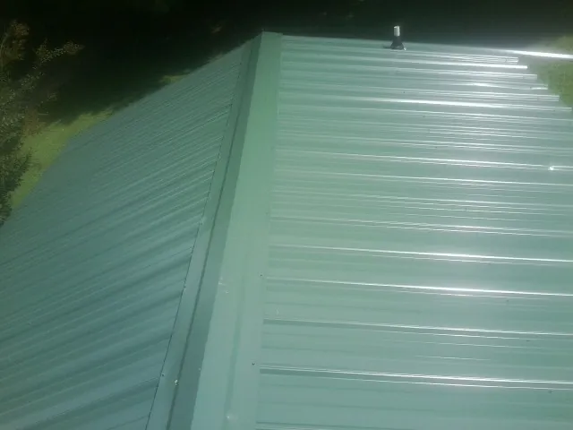 New green metal panels meeting at the ridge of a roof — Flat Roof Repair work by our crew in Laurelville