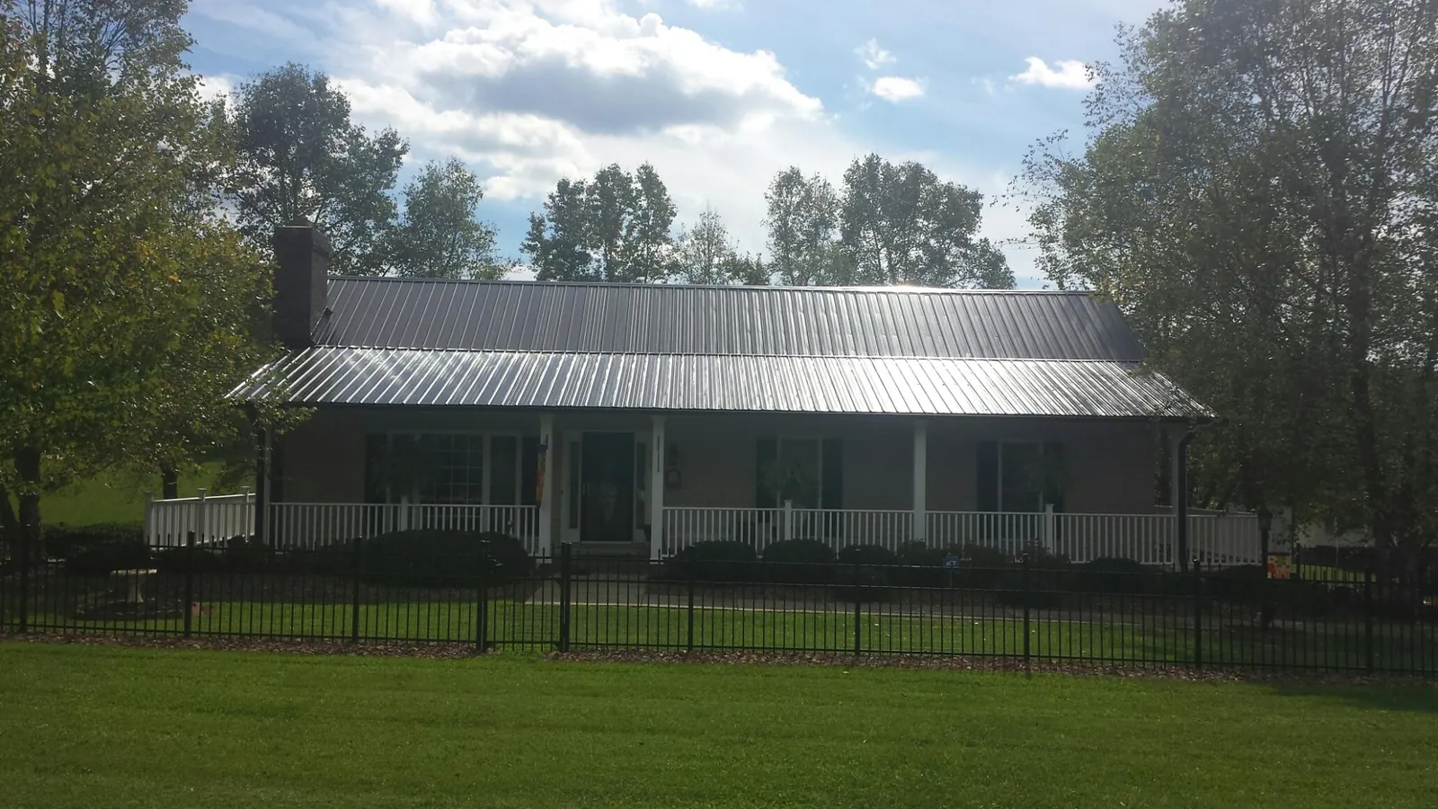 Gray metal roof on a brick ranch with a full width front porch — Gutter Guard Installation work by our crew in Laurelville